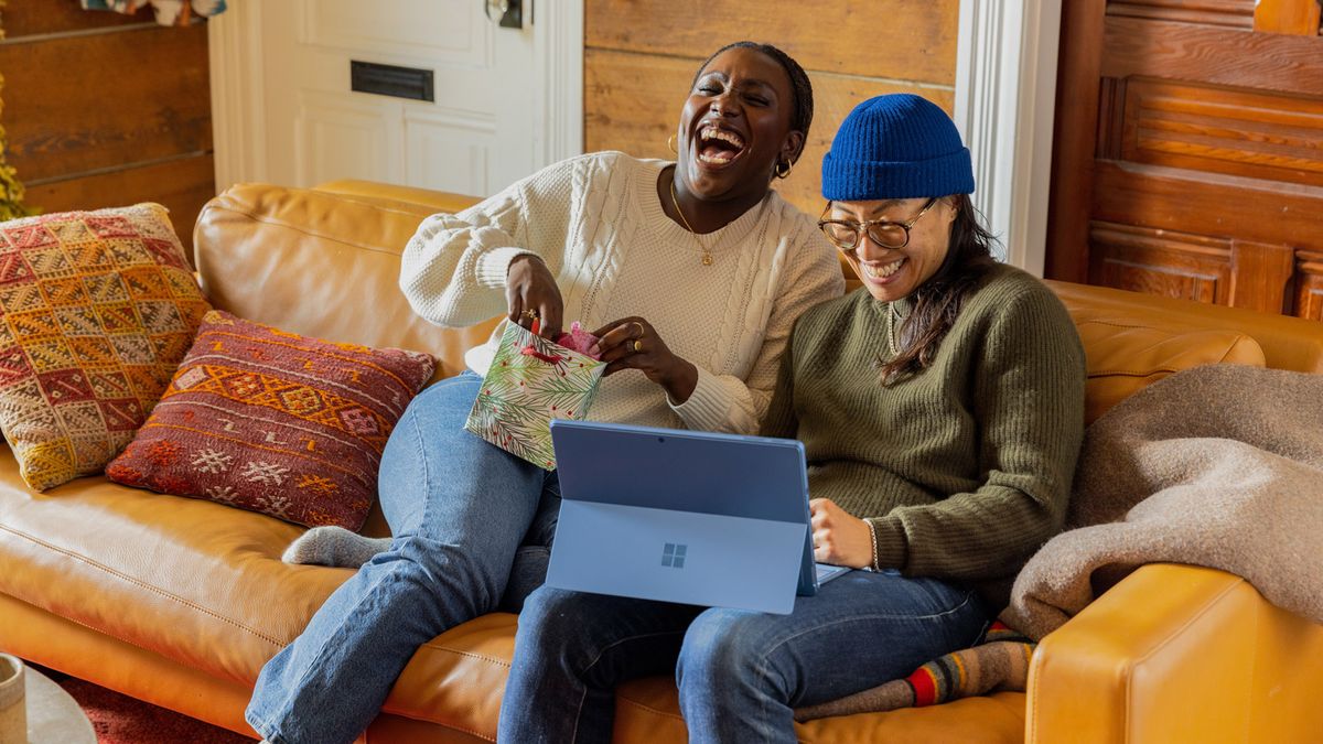 Female couple sitting on sofa with Microsoft Surface tablet