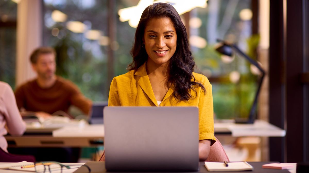 A young woman is working on a laptop in a relaxed office space.